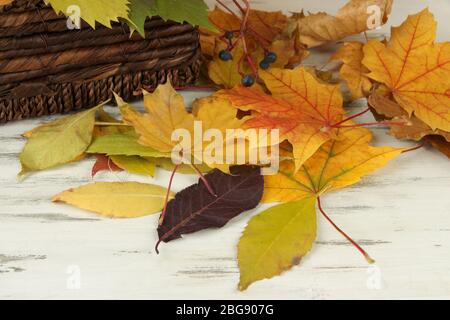 Belles feuilles d'automne avec panier sur fond de bois Banque D'Images