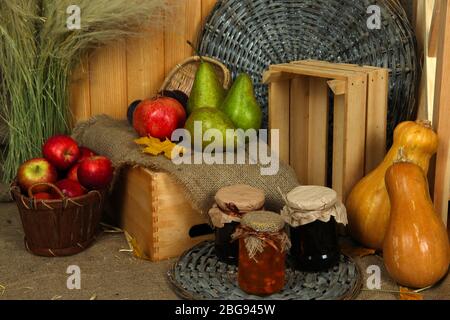 Fruits en caisse avec pot de confiture et citrouilles sur toile de fond en bois Banque D'Images