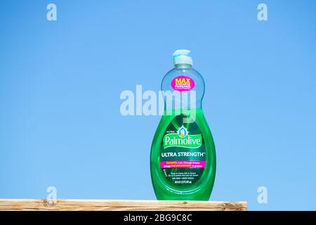 Une bouteille partiellement remplie de savon liquide vaisselle Palmolive contre fond bleu ciel. F Banque D'Images