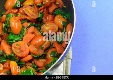 Faire revenir les tomates, les carottes et les épinards et l'ail dans une poêle anti-adhésive sur le support de la casserole Banque D'Images