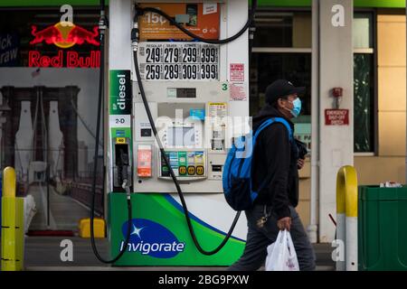 (200421) -- NEW YORK, le 21 avril 2020 (Xinhua) -- un homme portant un masque passe par une pompe à gaz à une station-service du quartier de Brooklyn, à New York, aux États-Unis, le 20 avril 2020. Les prix du pétrole américain ont été écrasés sur le territoire négatif pour la première fois dans l'histoire lundi, alimentés par un choc de la demande et des craintes de suroffre liées à la pandémie. Le West Texas Intermediate (WTI) pour la livraison de mai a versé 55,9 dollars américains, ou plus de 305 pour cent, pour régler à -37,63 dollars le baril sur le New York Mercantile Exchange, ce qui implique que les producteurs paieraient aux acheteurs de retirer le pétrole de leurs mains. (Photo de Michael Banque D'Images