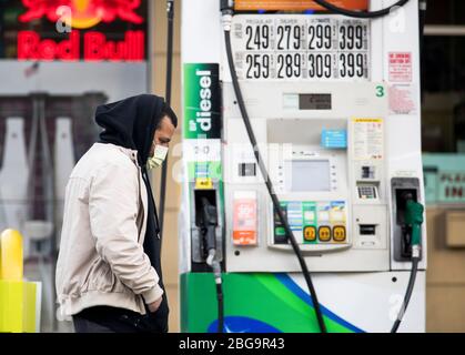 (200421) -- NEW YORK, le 21 avril 2020 (Xinhua) -- un homme portant un masque passe par une pompe à gaz à une station-service du quartier de Brooklyn, à New York, aux États-Unis, le 20 avril 2020. Les prix du pétrole américain ont été écrasés sur le territoire négatif pour la première fois dans l'histoire lundi, alimentés par un choc de la demande et des craintes de suroffre liées à la pandémie. Le West Texas Intermediate (WTI) pour la livraison de mai a versé 55,9 dollars américains, ou plus de 305 pour cent, pour régler à -37,63 dollars le baril sur le New York Mercantile Exchange, ce qui implique que les producteurs paieraient aux acheteurs de retirer le pétrole de leurs mains. (Photo de Micha Banque D'Images