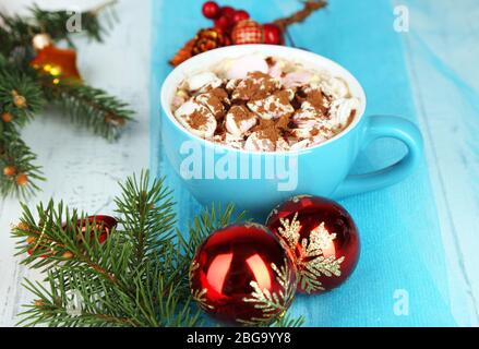 Chocolat chaud avec crème dans des mugs de couleur, sur table, sur fond de décorations de Noël Banque D'Images