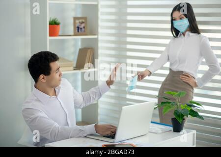 Femme dans un masque facial donnant un masque à sa collègue Banque D'Images