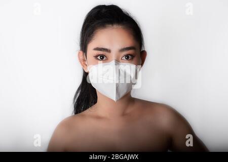 Gros plan sur la jeune femme asiatique qui a mis un masque médical n° 95 pour se protéger des maladies respiratoires aéroportées comme la grippe covid-19 PM2,5 poussière et smog au gr Banque D'Images