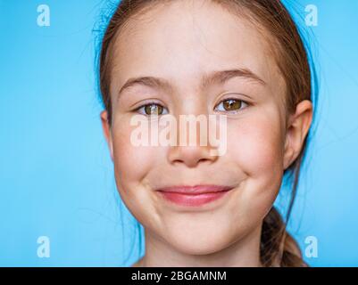 Portrait d'une belle fille souriante avec des taches regardant l'appareil photo. Modèle de bannière sur fond bleu Banque D'Images