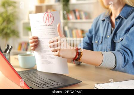 Gros plan sur les vidéos des étudiants montrant réussi l'examen sur la webcam de l'ordinateur portable avec des pouces sur un bureau à la maison Banque D'Images