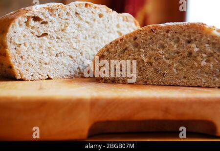 Deux pains de pain maison au levain sur une planche à découper en bois sur une table en bois dans un éclairage naturel Banque D'Images