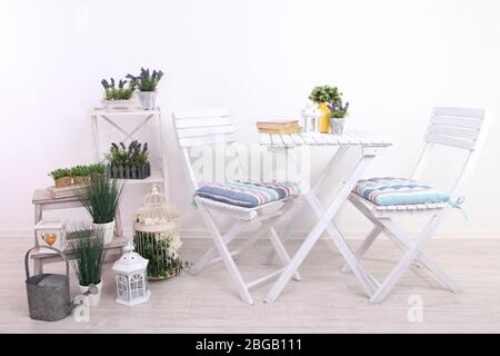 Chaises de jardin et table avec fleurs sur des supports en bois sur fond blanc Banque D'Images