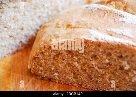 Deux pains de pain maison au levain sur une planche à découper en bois sur une table en bois dans un éclairage naturel Banque D'Images