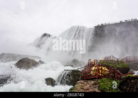 Chutes Niagara, NY, États-Unis - 13 juin 2019 : les visiteurs des manteaux de pluie dans un escalier en bois humide font une visite sous les éclaboussures des chutes américaines Banque D'Images