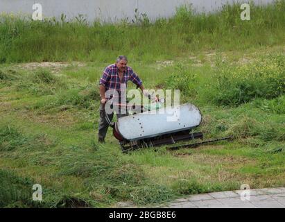 Une promenade à l'essence de taille industrielle derrière la tondeuse pour récolter l'herbe Travailleur isolé vu de l'avant Santander Cantabria Espagne Banque D'Images