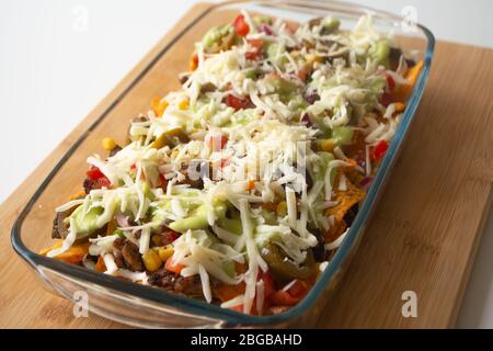 Nachos cuits au four avec chips de tortilla de maïs, maïs, guacamole, pico de gallo, haricots, jalapenos et Monterrey Jack dans un plat de cuisson en verre Banque D'Images