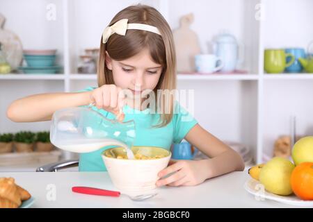 Belle petite fille manger le petit déjeuner dans la cuisine à la maison Banque D'Images