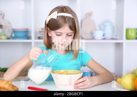 Belle petite fille manger le petit déjeuner dans la cuisine à la maison Banque D'Images