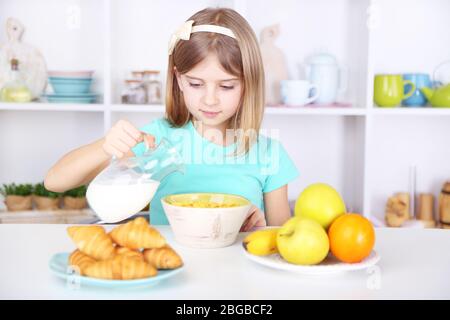 Belle petite fille manger le petit déjeuner dans la cuisine à la maison Banque D'Images