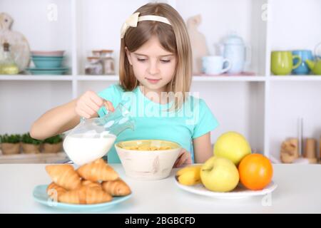 Belle petite fille manger le petit déjeuner dans la cuisine à la maison Banque D'Images