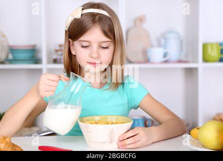 Belle petite fille manger le petit déjeuner dans la cuisine à la maison Banque D'Images