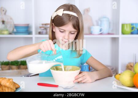 Belle petite fille manger le petit déjeuner dans la cuisine à la maison Banque D'Images