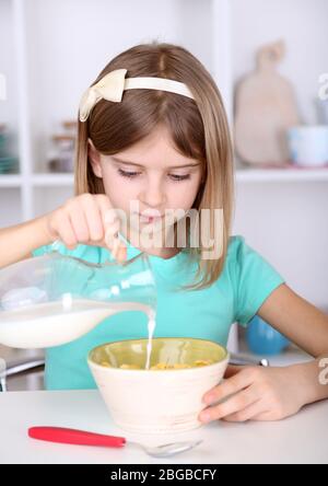 Belle petite fille manger le petit déjeuner dans la cuisine à la maison Banque D'Images