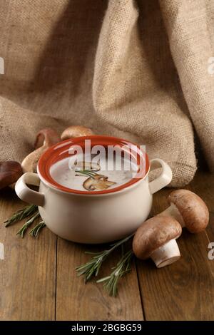Composition avec soupe aux champignons dans la casserole, champignons frais et séchés, sur table en bois, sur fond de toile de fond Banque D'Images