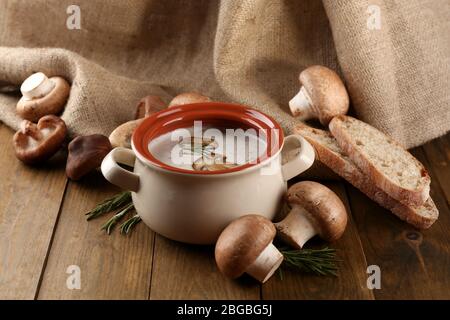 Composition avec soupe aux champignons dans la casserole, champignons frais et séchés, sur table en bois, sur fond de toile de fond Banque D'Images