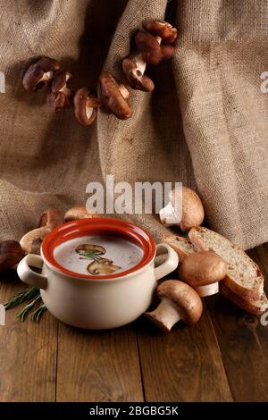 Composition avec soupe aux champignons dans la casserole, champignons frais et séchés, sur table en bois, sur fond de toile de fond Banque D'Images