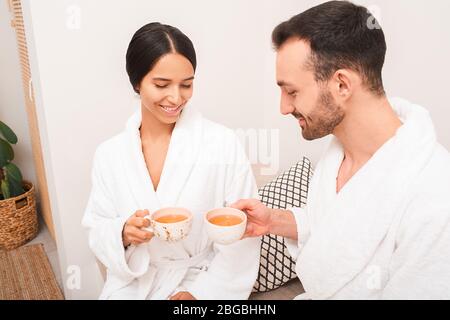 Beau couple mixte de course à boire un thé relaxant dans un spa. Date romantique dans un salon de spa Banque D'Images