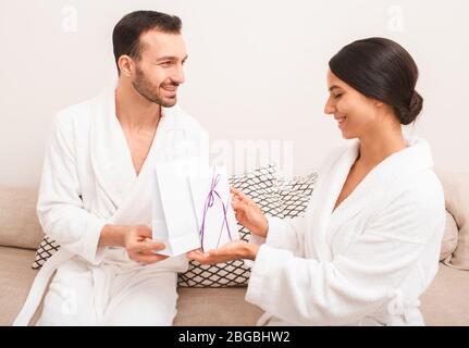 Un beau couple est très heureux avec un cadeau du certificat du salon de spa pour les visites de massage et de sauna. Homme et femme portant dans des peignoirs Banque D'Images