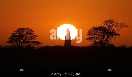 Le soleil se lève derrière le phare de St Mary, près de Whitley Bay, Northumberland. Banque D'Images