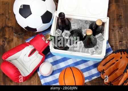 Glacière pleine de boissons dans des bouteilles sur une serviette de couleur, sur fond en bois Banque D'Images
