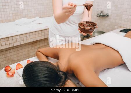 Enveloppement au chocolat dans le spa. Jeune femme obtenant un masque de chocolat sur son corps pour hydrater sa peau Banque D'Images