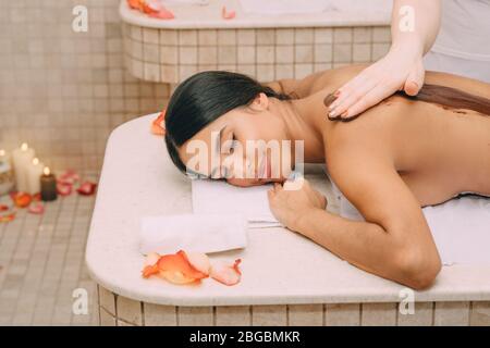 Belle femme bénéficiant de la procédure d'emballage au chocolat. La procédure de masque corporel au chocolat nourrit la peau de vitamines, de minéraux et d'antidépresseurs Banque D'Images