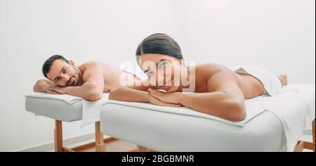 Femme de course mélangée souriant regardant l'appareil photo tout en se relaxant avec son petit ami dans un salon de spa. Couple après massage Banque D'Images