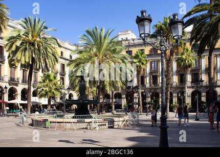 Vue sur les personnes accrochées sur une célèbre place de la ville appelée 'Placa Reial', palmiers et bâtiment historique traditionnel à Barcelone. C'est un soleil s Banque D'Images