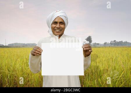 Un agriculteur indien tenant un tableau blanc avec le sourire sur son visage Banque D'Images