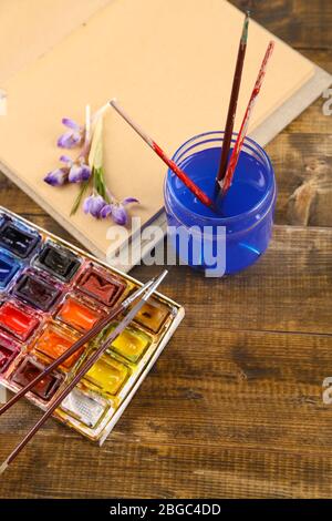 Composition avec aquarelles colorées, brosses et croquis sur fond en bois Banque D'Images