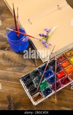 Composition avec aquarelles colorées, brosses et croquis sur fond en bois Banque D'Images