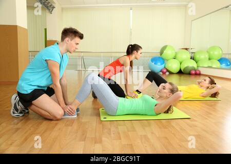 Jeune entraîneur et femme engagés dans la salle de gym Banque D'Images