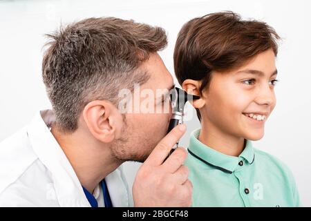 Pédiatre examinant peu de race mixte enfant avec otoscope, examen auditif de l'enfant Banque D'Images