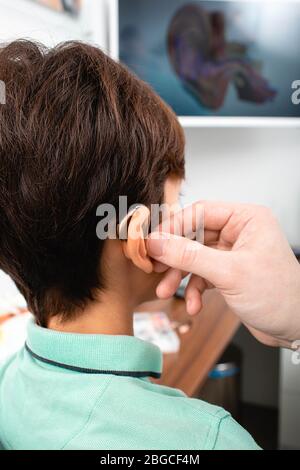 installation d'une aide auditive sur l'oreille de l'enfant. Traitement auditif à la clinique Banque D'Images