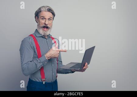 Profil vue latérale portrait de son sympathique sympathique homme plein de confiance stupéfié gai gai gai tenant dans les mains ordinateur portable montrant la promotion isolée sur gris Banque D'Images