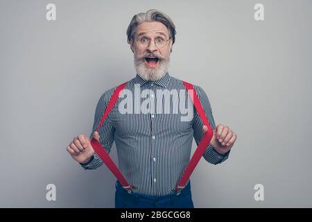 Portrait de son joli élégant chic élégant chic drôle drôle drôle drôle drôle drôle amusant gai gai homme tirant des jarretières ayant l'amusement isolé sur le pastel gris Banque D'Images