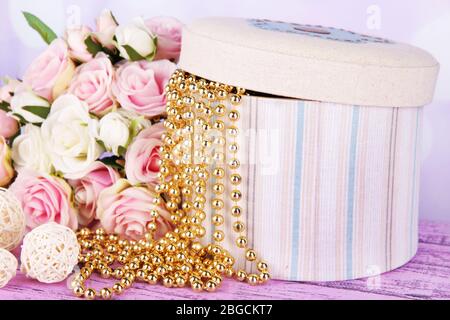 Boîte décorative avec perles et fleurs sur table sur fond lumineux Banque D'Images