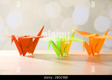 Grues Origami sur table en bois, sur fond clair Banque D'Images