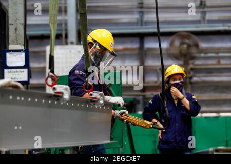 Les employés de l'usine Joroonrat Engineering travaillent sur une ligne de production de la clinique d'ARI modulaire (infection respiratoire aiguë) tout en portant des casques et des masques de protection comme mesure préventive pendant la crise de Coronavirus (COVID-19). L'usine produit des chambres modulaires de transport de patients et de cliniques ARI qui seront distribuées gratuitement aux hôpitaux dans le but de freiner la propagation du Coronavirus (COVID-19). Banque D'Images