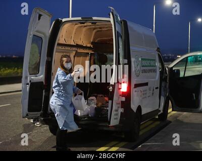 Inner City aider le volontaire sans-abri avril sombre mains hors des boissons chaudes, de la nourriture et des articles de toilette aux sans-abri et les traverses rugueuses dans le nord de Dublin pendant le verrouillage du coronavirus. Banque D'Images