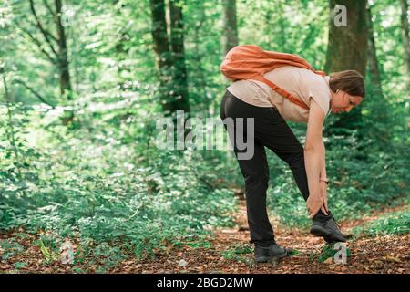 Female hiker avec blessure à la cheville en forêt à l'extérieur lors de l'activité de trekking, selective focus Banque D'Images