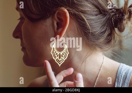 Femme portant des boucles d'oreilles en laiton sous forme de lotus oriental Banque D'Images