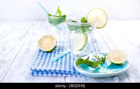 Deux verres d'eau avec des citruses et de la menthe sur fond blanc. Boisson rafraîchissante en été. Espace de copie. Banque D'Images